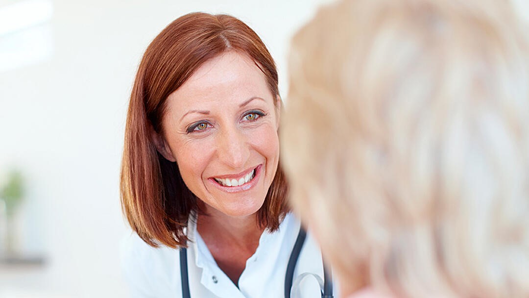 Redheaded female doctor speaks to a female patient